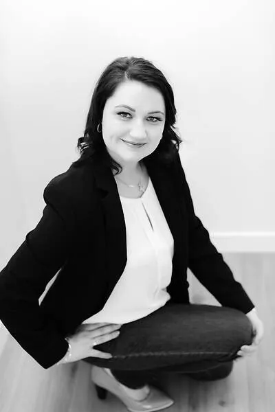 Studio portrait of Annelize seated, in a navy blazer